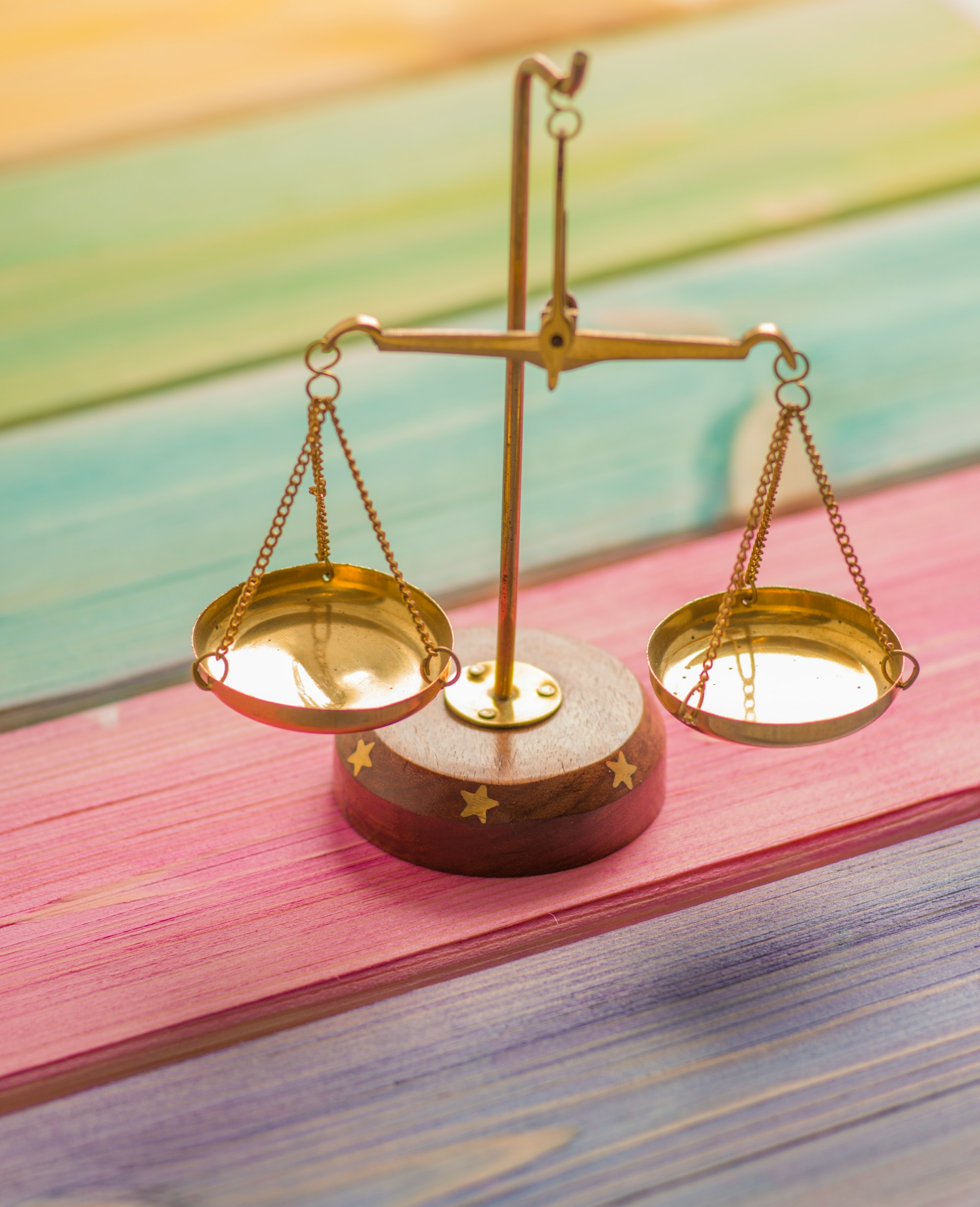 Petite balance dorée sur du bois coloré, par Elena Mozhvilo sur Unsplash