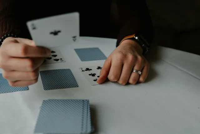Personne tenant des cartes à jouer sur une table blanche, par Andrik Langfield sur Unsplash