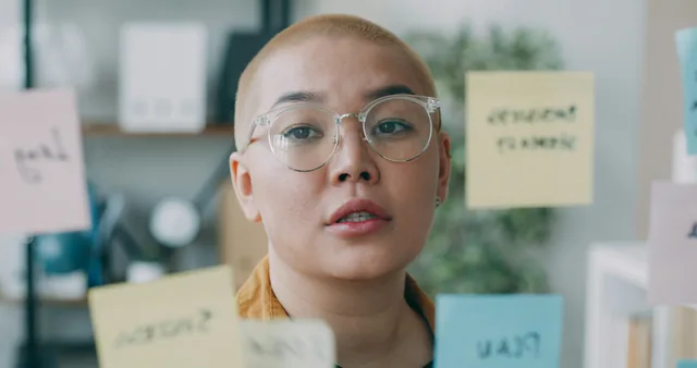 Product Owner organisant des post-its sur un tableau en verre pour prioriser le backlog produit