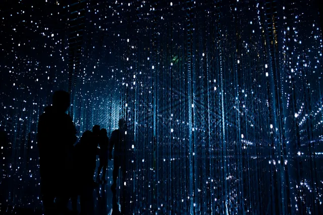 Silhouettes de personnes immergees dans une installation lumineuse numerique evoquant le futur de l'IA